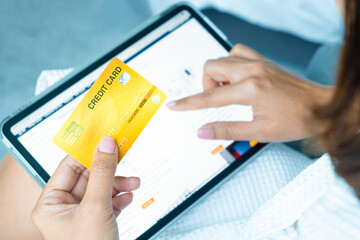 Woman holding credit card and he is shopping online on tablet and using credit card to pay bills concept of finance and banking
