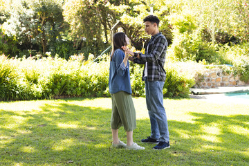 Obraz premium Happy diverse couple holding hands and looking at each other in sunny garden, copy space