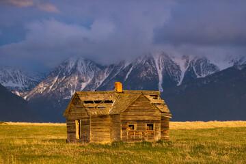 beautiful old rustic cabin with majestic mountains at sunset
