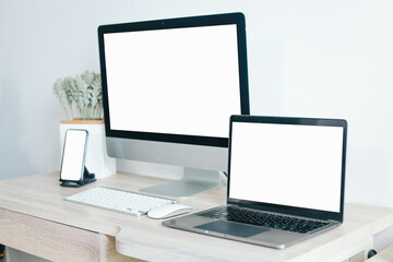Mockup of laptop computer and mobile phone with white blank screen on office table 