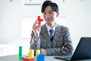 ブロックを持ち考える若いジャケットを着た男性