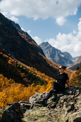 a girl with a backpack stands in the autumn mountains