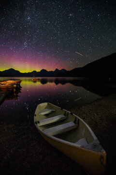 boats on lake at night with northern lights reflection 