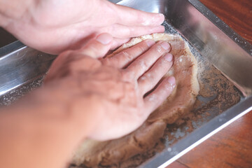 Fototapeta premium Hands of man kneading dough while making bread in the kitchen 