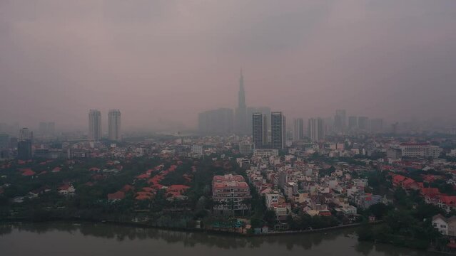 Aerial view of air pollution in southeast asian city. Location is Ho Chi Minh City, Vietnam with Saigon River, Thao Dien and city skyline. Dolly shot of panorama.