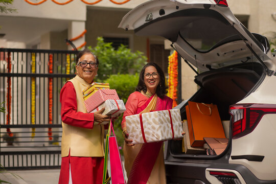 Senior couple unloading Diwali gifts from car trunk after shopping