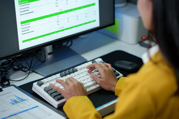 Successful Asian businesswoman sitting at desk typing numeric data on PC keyboard in modern office Business technology career concept.