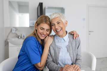 The elderly woman enjoys an embrace from her favorite healthcare doctor. Medical care, young female doctor hugging patient. Empathy concept. Elderly woman hugging caregiver - obrazy, fototapety, plakaty