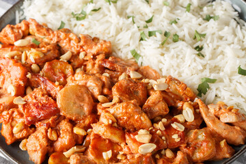 Classic Swedish Dish Flygande Jakob made of chicken, cream, chilli sauce, bananas, roasted peanuts and bacon served with rice closeup on the plate on the table. Horizontal