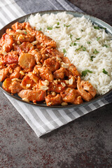 Flying Jacob is a Swedish casserole composed of chicken, cream, chilli sauce, bananas, roasted peanuts and bacon served with rice closeup on the plate on the table. Vertical