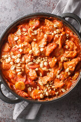 Flying Jacob is a Swedish casserole composed of chicken, cream, chilli sauce, bananas, roasted peanuts and bacon closeup on the pan on the table. Vertical top view from above