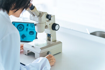 顕微鏡で観察する白衣の女性
