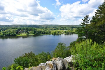 Scenic view across the Connecticut River with low stone wall in the foreground and cloudy blue sky above