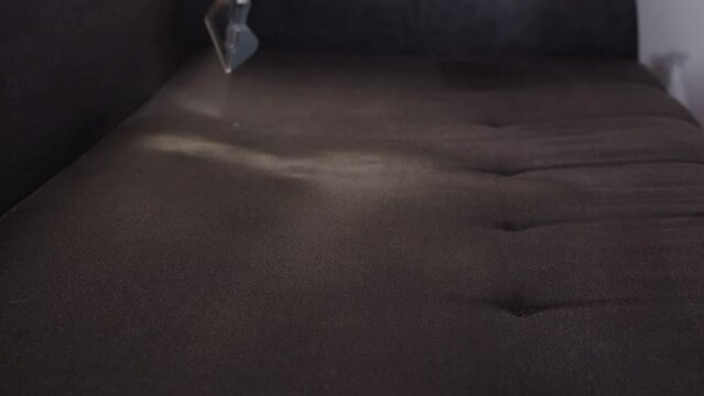Applying a special cleaning solution to clean stains and dirt on upholstery of upholstered furniture. The first stage of dry cleaning. Slow motion. Copy space for text