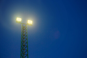 Bright floodlights at a sports stadium against midnight blue sky