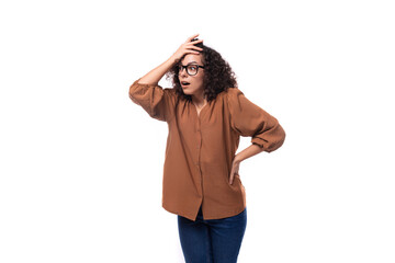 young surprised european curly woman with curled hair on a curling iron is dressed in a brown shirt