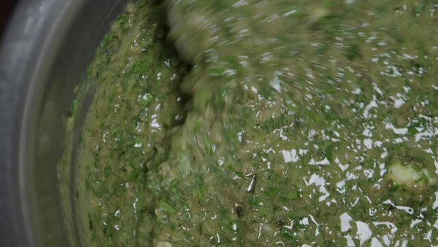 The ingredients for a delicious herb butter are stirred in a metal bowl. Close-up, no face.
