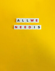 All We Need Is Phrase on Block Letter Tiles on Yellow Background. Minimal Aesthetic.