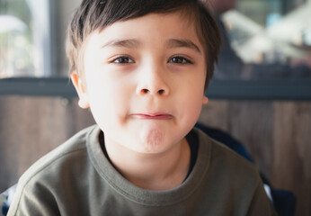 Photo of funky happy cheerful young little boy make funny face, Portrait of good mood a preschool kid making fun with lips looking at camera on blurred background