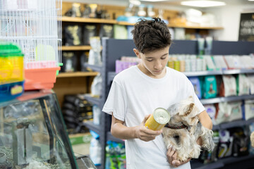 Teenage boy with puppy Yorkshire terrier in arms and carefully read composition of product at...