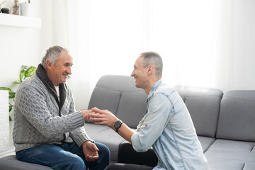 Grown up son asking for apologizes to offended stressed elderly senior daddy, sitting together on couch. Compassionate young man supporting, giving psychological help to frustrated middle aged father. - obrazy, fototapety, plakaty