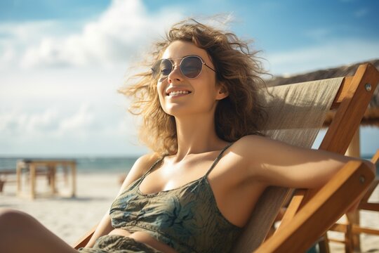 Portrait of happy young woman relaxing on wooden deck chair at tropical beach