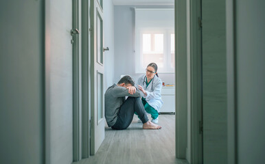 Female psychiatrist talking to male patient with mental disorder and suicidal thoughts sitting on...