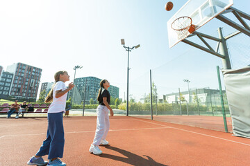 Streetball basketball game with two players, teenagers girls, morning on basketball court.