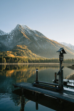 kleiner Steg am Hintersee bei Sonnenuntergang mit dem verschneiten Hochkalter im Herbst