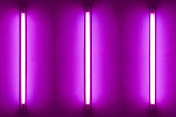 Three purple neon bulbs on white wall. Background texture of empty old wall with glowing purple...