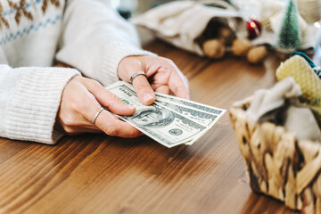 Girl counting US Dollar bills, and planning expenses for Christmas. Woman doing budget, estimating...