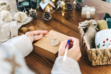 Woman s hands wrapping Christmas gift boxes, close up. Unprepared presents on white table with...