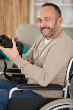 male photographer on wheelchair holding camera indoor