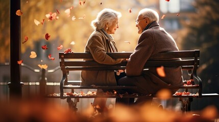 Senior couple sitting on garden bench in autumn with falling leaves. Tenderness and complicity - obrazy, fototapety, plakaty