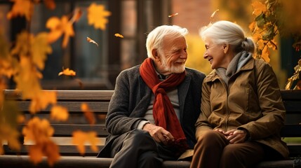 Senior couple sitting on garden bench in autumn with falling leaves. Tenderness and complicity - obrazy, fototapety, plakaty