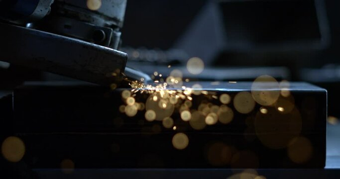 Super slow motion macro of blacksmith welder is smoothing metal steel with industrial angle grinder with flying sparks in workshop.