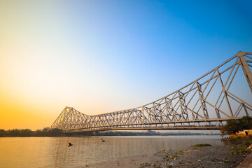 Historic Howrah bridge Kolkata at sunset with blue sky.