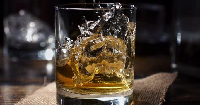 Super slow motion macro of transparent fresh cool ice bounced by bartender while preparing an old malt bourbon Whiskey cocktail at 1000 fps.