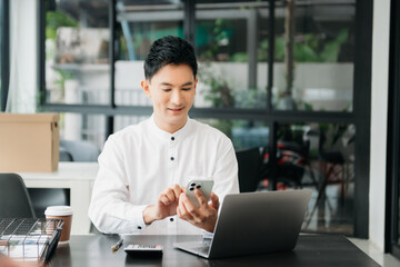 Asian man sitting at a desk using a laptop computer Navigating Finance and Marketing with Technology
