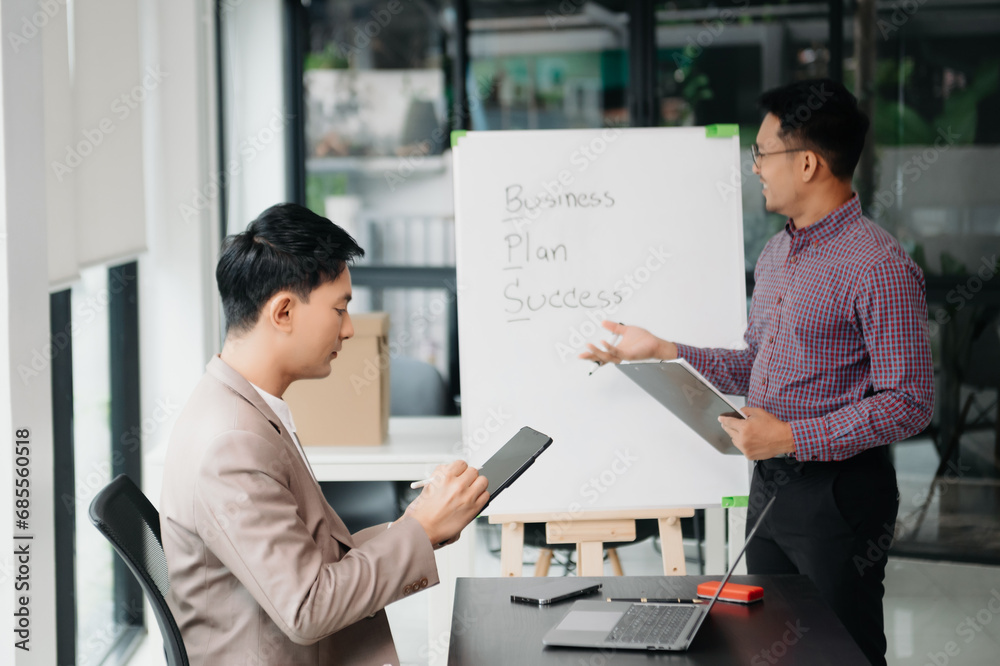 Wall mural Businessman leading team meeting and using tablet and laptop computer with financial in co working office