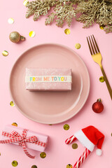 Plate, gift box, Christmas candy canes and decorations on pink background, top view