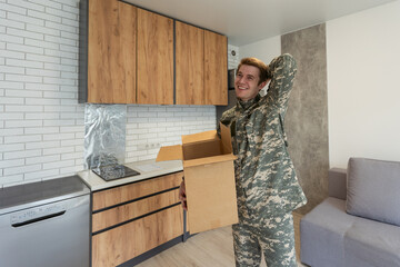 Patriotic military man in uniform keeps box in new apartments. Buying a property