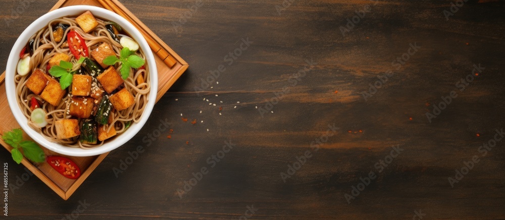 Poster top view of a bowl with soba noodles vegetables and fried tofu copy space image
