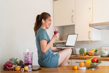Woman using personal laptop with blank empty screen with copy space, looking for new healthy recipe...