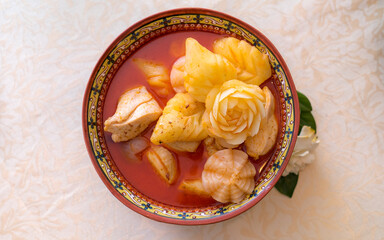 Chicken Mussaman Curry in bowl on leaves fabric background. Traditional Thai food. Craft potatoes in flower and leaf shape.