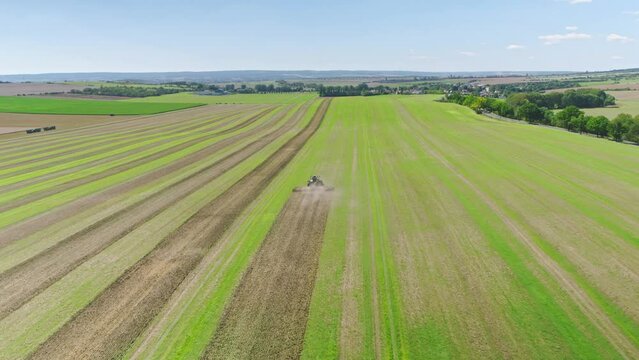 Machines till the fields for the coming harvest year. Wide angle drone shot.