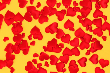 Texture made of textile red confetti in a heart shape on a yellow background. Festive concept.
