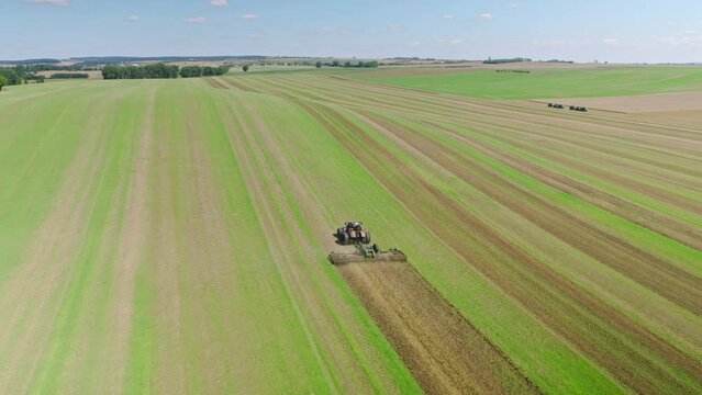 Machines till the fields for the coming harvest year. Wide angle drone shot.