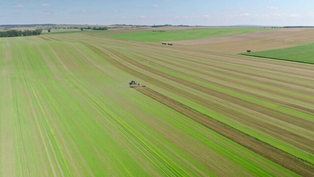 Machines till the fields for the coming harvest year. Wide angle drone shot.