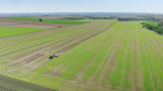 Machines till the fields for the coming harvest year. Wide angle drone shot.